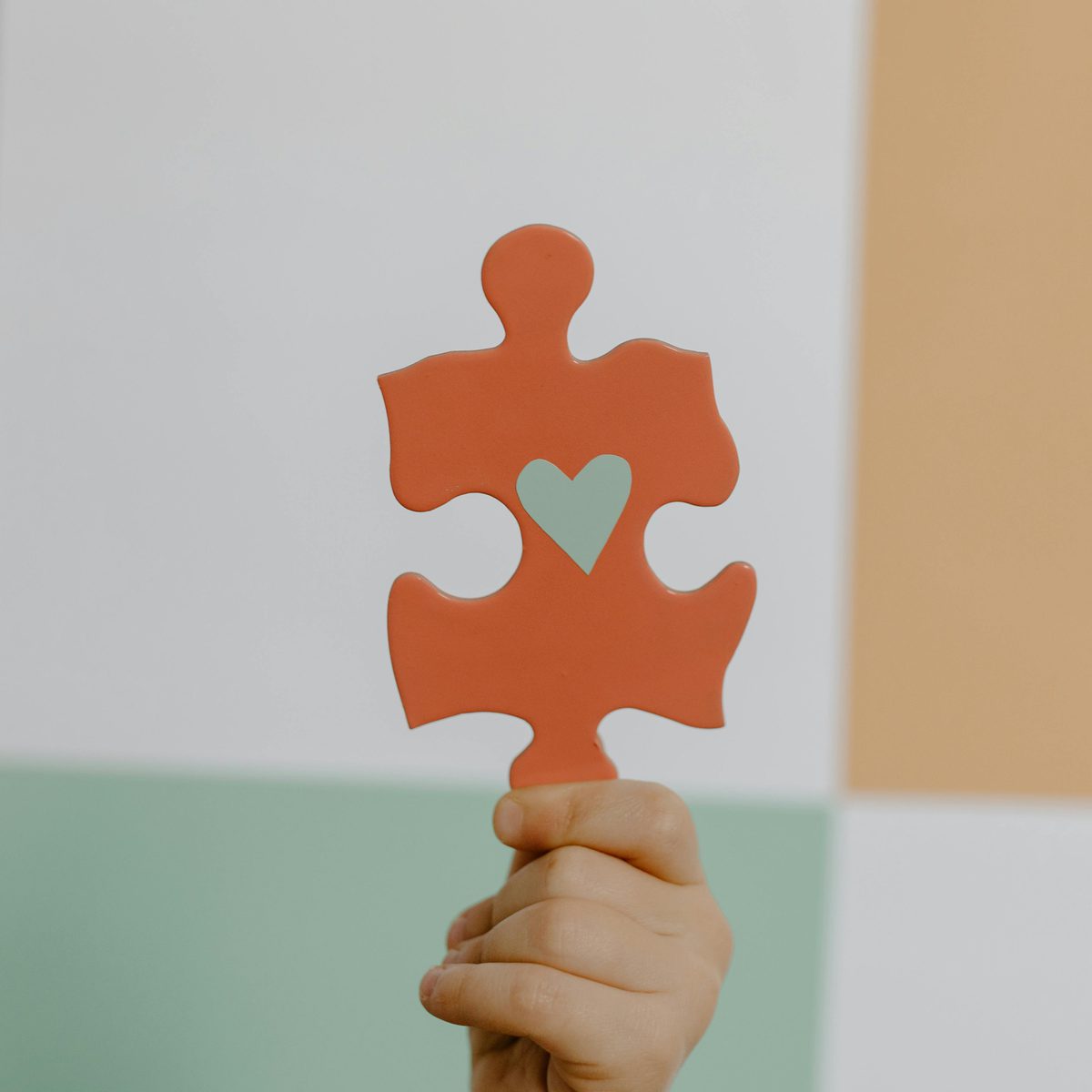 Orange puzzle piece with green heart held in hand, symbolizing the pieces that make effective nonprofit fundraising
